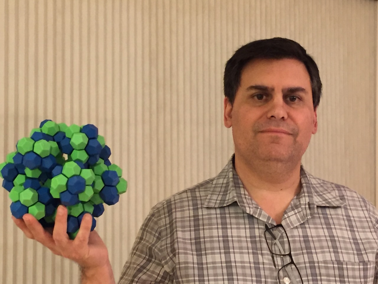 A picture of the author holding a green and blue sculpture that looks like a model of a molecule.